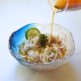 A close-up of a bowl of Japanese somen noodle soup with a glass of mentsuyu. yunomi.life